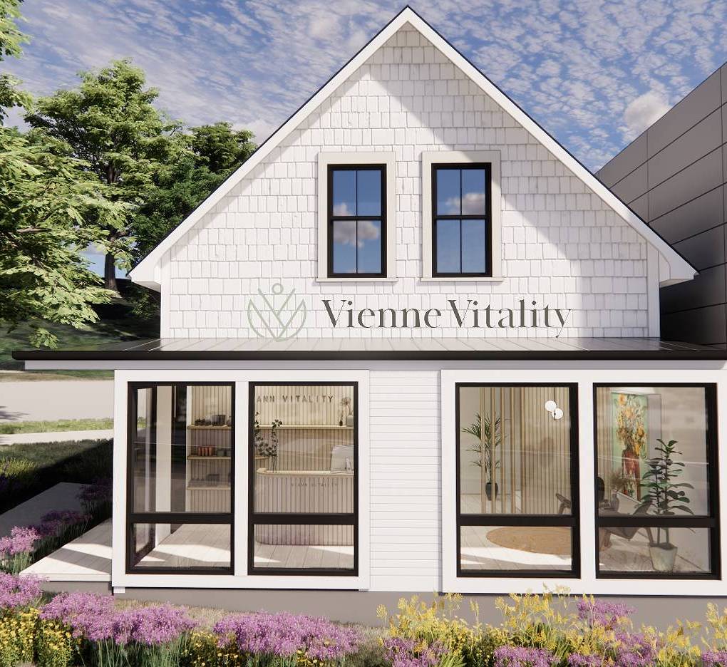 A modern white two-story house with large front windows and a garden of purple flowers, trees, and grass. “Vienne Vitality” and a leafy logo appear above, highlighting care for midlife wellness and menopause guided by certified practitioners.